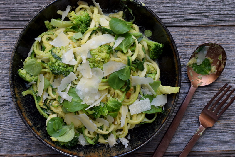 Bovenaanzicht: donker bord met courgetti met cashewsaus en broccoli