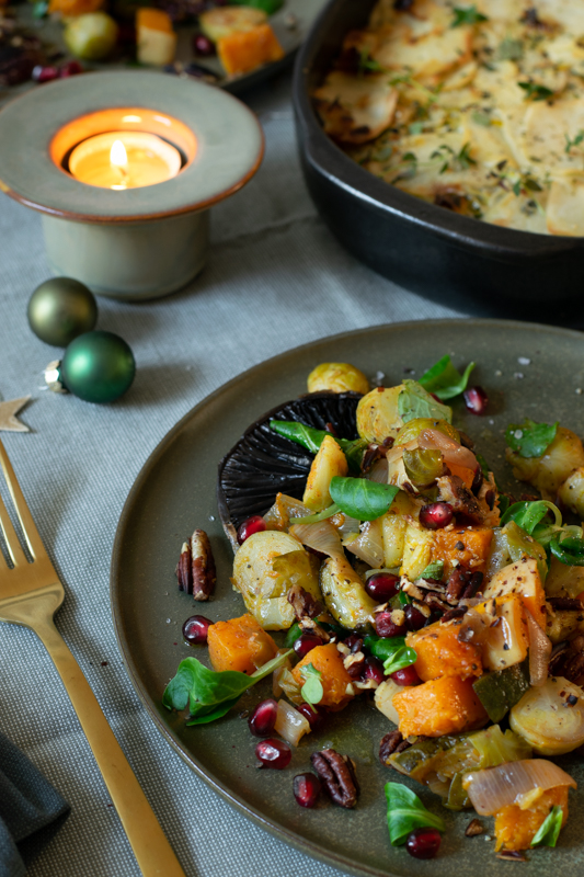 Zijaanzicht: geroosterde wintergroenten en op de achtergrond een ovenschotel met aardappel-preigratin