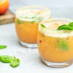 Fizzy nectarinemocktail. Twee lage, bolle glazen met een perzikkleurig, schuimend aperitief.